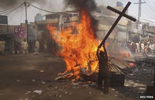 A rioter burns a cross in Lahore, 9 March