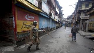 An Indian paramilitary soldier orders a pedestrian to go back during a curfew in Srinagar, India, Thursday, March 14, 2013.