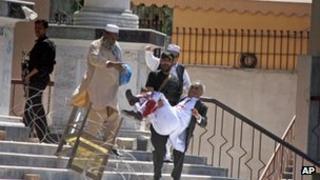 A Pakistani police officer carries an injured man outside the court complex in Peshawar, Pakistan, Monday, March 18, 2013.