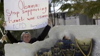 Palestinian man holds banner urging US to stop supporting Israel during protest against Mr Obama's visit.