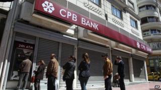 People queue to use the ATM of the Greek branch of Cyprus Popular Bank in Athens