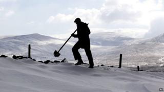 A man silhouetted against a white snowy hillside