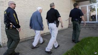 Kaufman county law enforcement officials escort an employee inside the county courthouse 1 April 2013 Kaufman, Texas