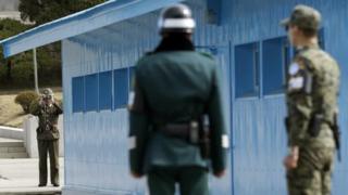 A North Korean soldier (left) looks through binoculars at South Korean soldiers at the border village of Panmunjom. Photo: March 2013