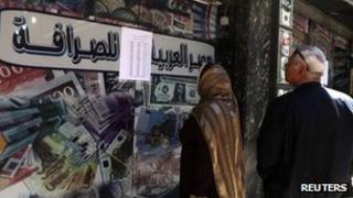People look at the currency exchange rates outside of an exchange bureau in central Cairo
