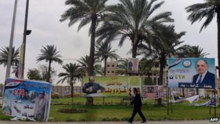 An Iraqi walks past campaign billboards in Baghdad
