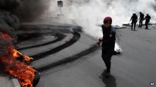 Riot police extinguish a row of burning tires set ablaze by Bahraini anti-government protesters, not pictured, on a street in Jidhafs, Bahrain, Sunday, April 21