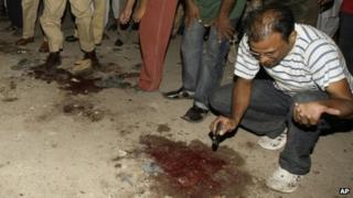 Police gather at the site of the attack on the MQM offices in Karachi