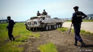 Congolese government policemen walk alongside a United Nations armoured personnel carrier at the airport in Goma, eastern Democratic Republic of the Congo