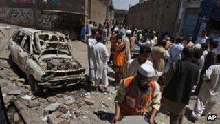 People gather at the site of an explosion outside an election office of a candidate in Peshawar, Pakistan, 28 April 28, 2013