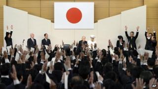 Japan's Prime Minister Shinzo Abe (top left) and attendees cheer in front of Emperor Akihito (C) and Empress Michiko (C)