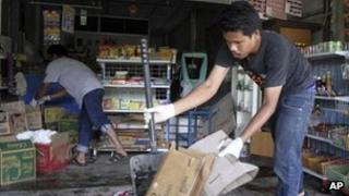 Workers clean the debris following Wednesday night's shooting outside a grocery store in Pattani province, southern Thailand, 2 May 2013