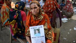 The mother of a woman who worked inside Rana Plaza holds up a picture of her (9 May 2013)