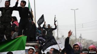 A Syrian rebel raises his weapon while waving an Islamist flag during an anti-regime protest in the northern city of Aleppo on March 22, 2013.