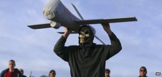 John Amidon holds up a model of an Air Force drone while protesting outside Creech Air Force Base, Wednesday, March 27, 2013, in Indian Springs