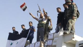 Forces loyal to the Syrian army wave national flags as they celebrate in the main square of Qusair in Syria's central Homs province