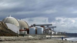 A man walks his dog next to the damaged San Onofre power plant located next to San Onofre State Park in California 8 November 2012