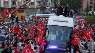 Supporters of Prime Minister Erdogan gather around his convoy waving flags