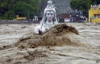Flood waters gush around a giant statue of Lord Shiva in the holy city of Rishikesh in Uttarakhand state