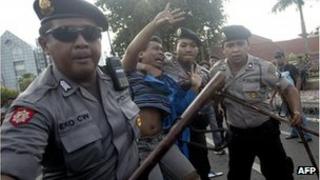 Indonesian police arrest a demonstrator following clashes at a protest over fuel price increase in Surabaya on June 21