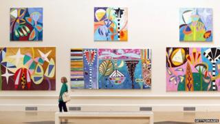 A visitor looks at paintings hanging at The Royal Academy Summer Exhibition
