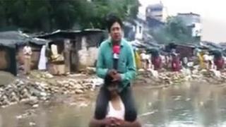 Narayan Pargaien on shoulders of a man who is standing in flood waters