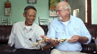 Dr Sam Axelrad, right, hands over arm bones belonging to former North Vietnamese soldier Nguyen Quang Hung at Hung's house in Gia Lai province, Vietnam on 1 July 2013
