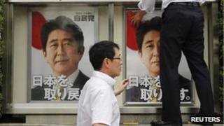 Staff members of Japan's ruling Liberal Democratic Party (LDP) put up posters of Japan's Prime Minister Shinzo Abe, who is also leader of the LDP, at the LDP headquarters in Tokyo, 4 July 2013