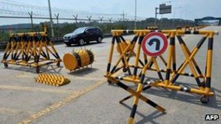 A car drives past barricades on the road linking North Korea's Kaesong Industrial Complex at a military check point in Paju near the demilitarized zone dividing the two Koreas on 6 June 2013