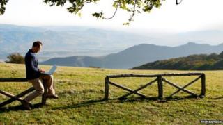 A man on his laptop in the countryside