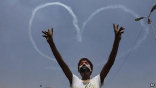 An Egyptian protester flashes v signs for military aircrafts forming a heart shape in the sky over Tahrir Square in Cairo, Egypt,, July 5, 2013.