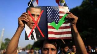 An opponent of Egypt's Islamist President Mohammed Morsi holds up a picture showing the United States President Barack Obama and US flag during a rally outside the Presidential palace in Cairo, Egypt, 7 July 2013