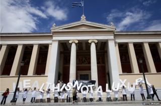 Members of the French medical charity Medecins du Monde (MDM, Doctors of the world) hold letters reading 'health is not a luxury ' outside the University of Athens