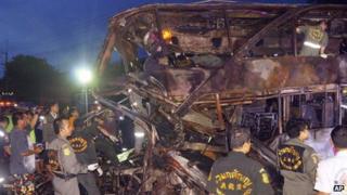 Rescue workers at the charred wreckage of a double-decker passenger bus after an accident in Saraburi province, northeast of Bangkok, Thailand 23 July 2013