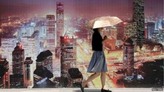 Beijing resident walks past wall bearing image of skyscrapers (23 July)