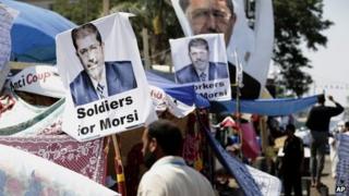 A supporter of Egypt's Islamist President Mohammed Morsi in front pictures of President Mohammed Morsi at Nasr City