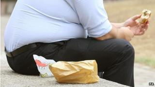 Overweight man eats sandwich