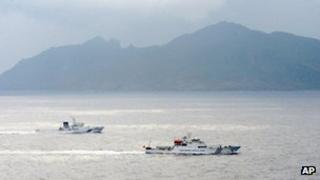 A Japan Coast Guard vessel, left, sails along with a Chinese surveillance ship, right, near disputed islands, rear, called Senkaku in Japan and Diaoyu in China in the East China Sea, 23 April 2013
