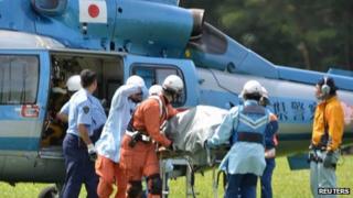 Rescue workers transport an unconscious South Korean hiker on a stretcher from a helicopter in Komagane, Japan, 30 July 2013