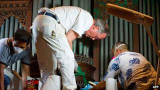 A crew removes green paint from an organ at the Washington National Cathedral, in Washington DC on 30 July 2013