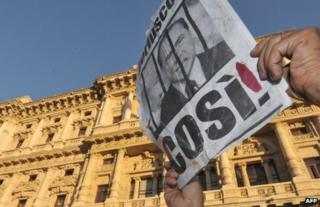 A person holds up a poster portraying Silvio Berlusconi behind bars in Rome, 1 August