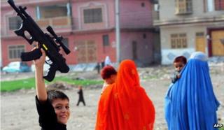 A Pakistani boy, fleeing from military operations against Taliban in the Pakistani tribal region, plays with toy guns