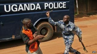 An Uganda policeman batons a journalist in Kampala on 28 May 2013, outside the Daily Monitor and Red Pepper newspapers, which were closed on May 20 by armed police