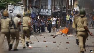 Indian policemen chase Hindus protesting against the state government after rival communities clashed in Kishtwar