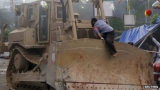 A supporter of deposed Egyptian President Mohamed Morsi jumps on a bulldozer clearing their sit-in site of the past six weeks at Rabaa Adawiya square in Cairo, 14 August, 2013.