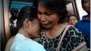 A survivor (L) reacts as she is reunited with a relative outside the ferry company's office in Cebu City
