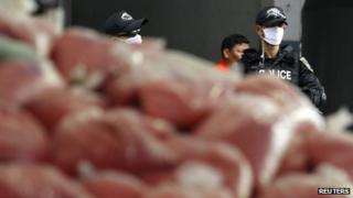 Thai policemen guard bags of methamphetamine pills