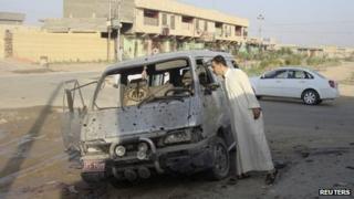 A man inspects a damaged vehicle a day after a car bomb attack in Dujail (23 August 2013)