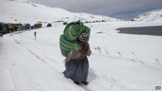 A woman walks along a snowy road on the outskirts of La Paz, Bolivia on 25 August 2013