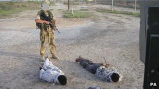 An unidentified British soldier stands over some of the detainees who have since given evidence to the inquiry in a photograph handed out by the inquiry